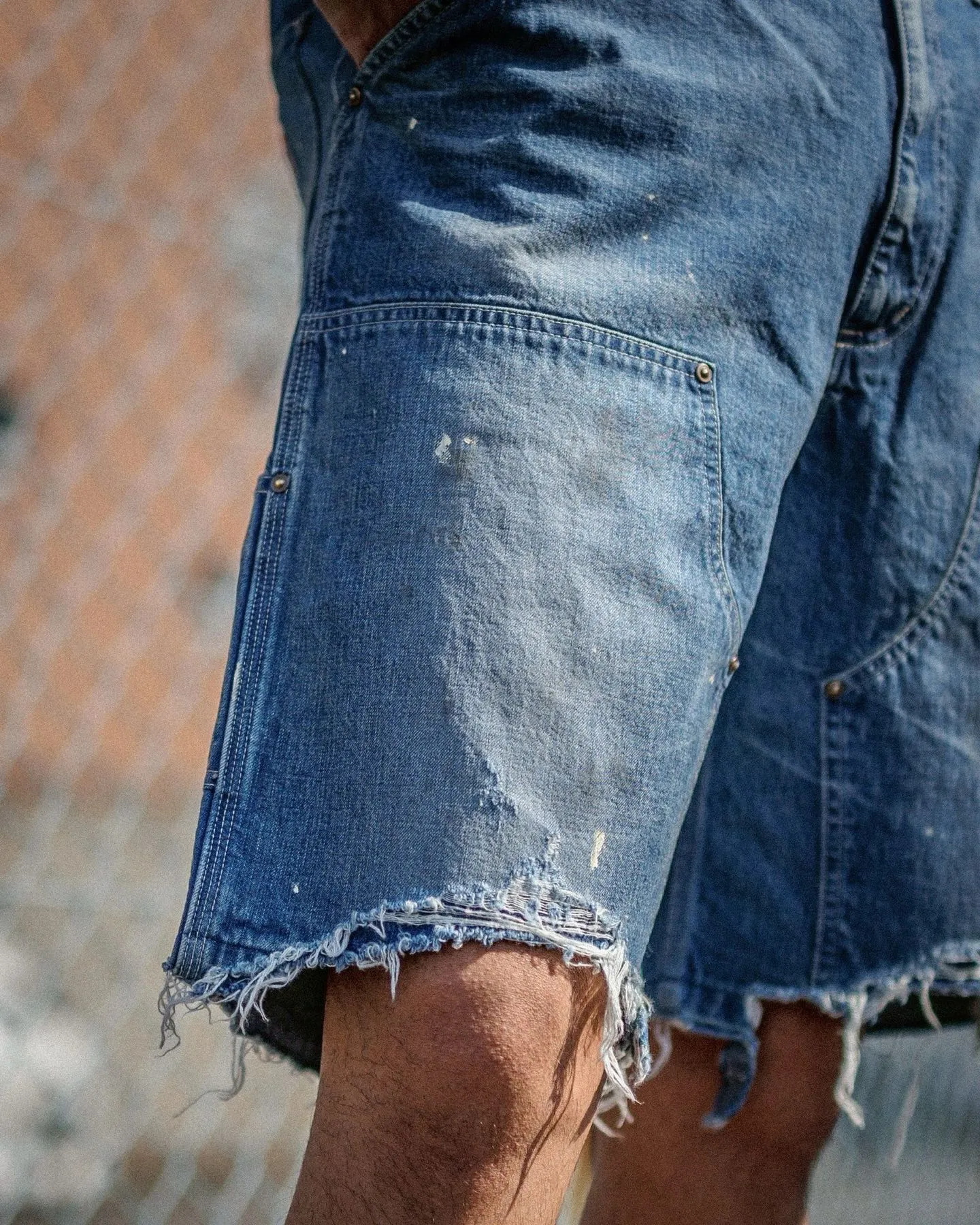 SAINT Mxxxxxx DOUBLE KNEE SHORTS/BLU Knee patches splashed with ink and water-splashed denim shorts. Denim blue S-XL. Custom-woven and dyed denim fabric with clear texture. Heavy-wash water-fading treatment to create local mottled fading/hole effects. Artificial distressing to simulate natural wearing marks. VINTAGE sense. Original consistent damage treatment. Hand-splashed ink and paint. Original consistent wash mark/pocket mark. Double knee patch. Rivet reinforcement. Improve functionality while enhancing design